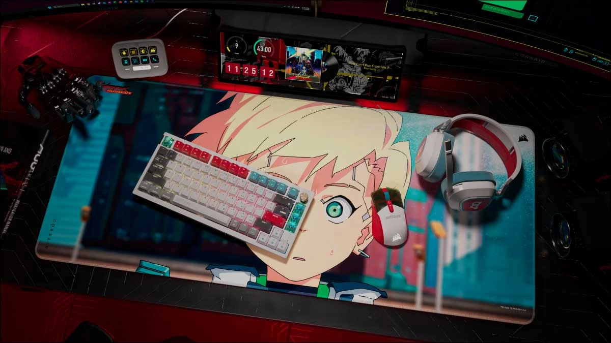 Secretária com o teclado, o rato, o headset e o tapete gigante da coleção Cyberpunk: Edgerunners 2 da Corsair