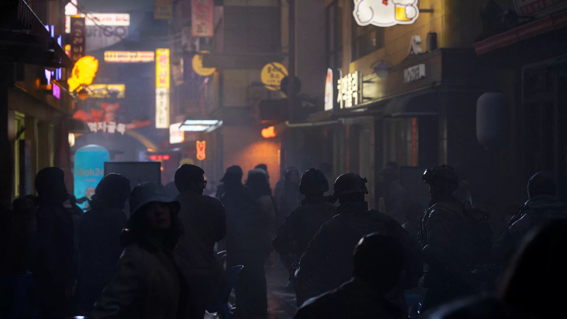 Rua de uma cidade coreana à noite, cheia de néons e de soldados, em Modern Warfare 4